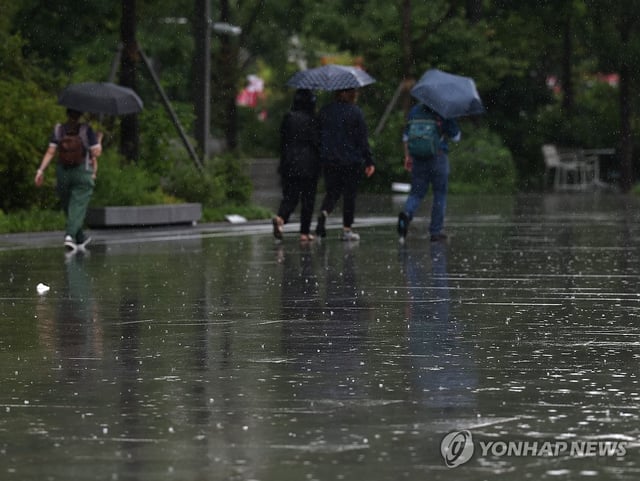 A file photo, taken July 8, 2024, shows people holding umbrellas amid monsoon rain at Gwanghwamun Square in central Seoul. (Yonhap)