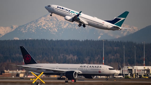 An Air Canada flight taxis to a runway as a WestJet flight takes off at Vancouver International Airport, in Richmond, B.C., on Friday, March 20, 2020. THE CANADIAN PRESS/Darryl Dyck