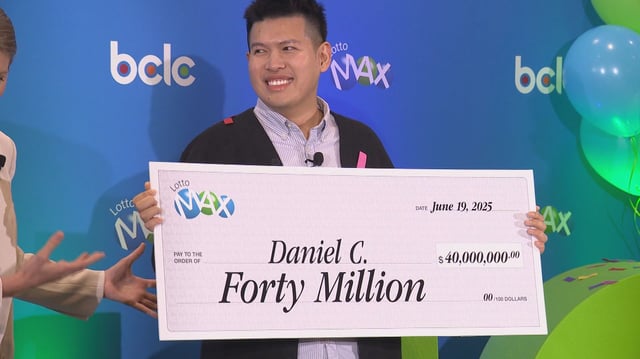 Daniel Chau grins as he's handed a $40 million lottery cheque. 