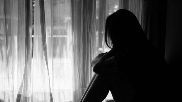 black and white of sad woman hug her knee and cry. Sad woman sitting alone in a empty room beside window or door (Siam - stock.adobe.com)