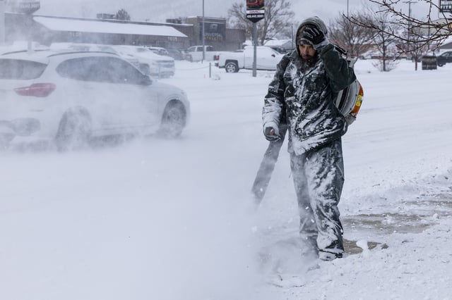 Kenny Austin uses a leaf blower to clear snow as temperatures hovered at -23 degrees on Friday, Jan. 12, 2024 in Helena, Mont. (Thom Bridge/Independent Record via AP)