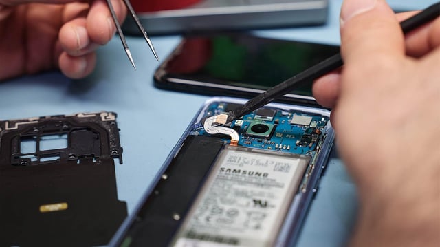 Ein Techniker repariert ein Smartphone mit defektem Display.