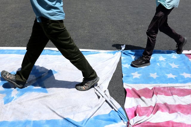 Iranians step on Israeli and American flags during a rally in Tehran