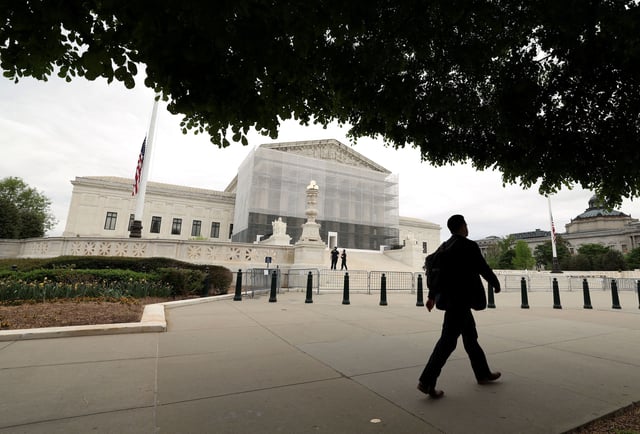 A person walks past the U.S. Supreme Court in Washington, D.C., U.S., April 21, 2025. REUTERS/Kevin Lamarque