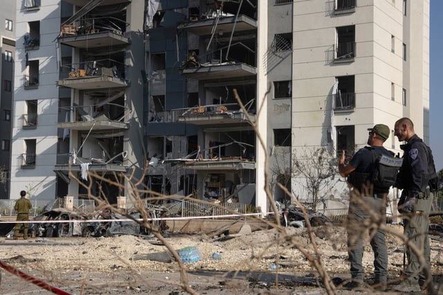 Members of the Israeli security forces check the destruction in front of a residential building hit during an Iranian missile attack in Beersheba in southern Israel, on June 20, 2025.
