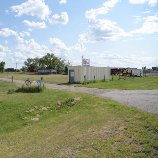 A sign along a side road parallel to Highway 3 reads, “Trudeau’s government demands up to 10 years prison time for Coutts protesters,” across from a shipping container marked Faith Mission, which is collecting used clothing and bicycles, in Taber, Alta., on Wednesday, June 4, 2025. The South Zone, which includes the town, accounts for the majority of Alberta’s confirmed measles cases. (Sarah B. Groot/The Globe and Mail)