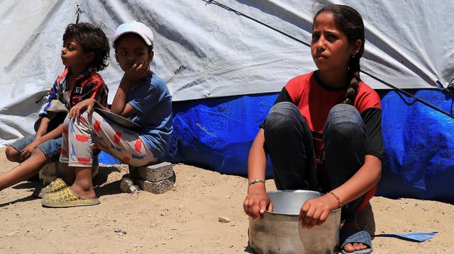 Vertriebene palästinensische Kinder sitzen in Gaza-Stadt vor einem Zelt.
