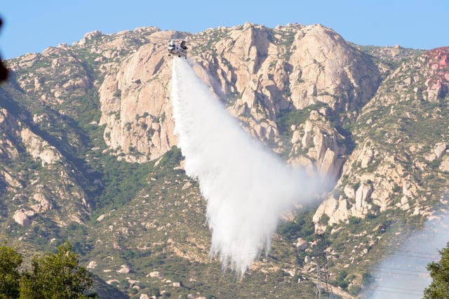 A helicopter working the Monte fire near Lakeside makes a water drop on a hot spot north of the El Monte County Park on Tuesday (Nelvin C. Cepeda / The San Diego Union-Tribune)