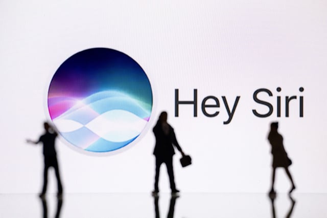 This illustration photograph taken on October 30, 2023, in Mulhouse, eastern France, shows figurines next to a screen displaying a logo of Siri, a digital assistant of Apple Inc. technology company.