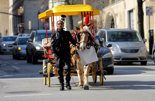 Baltimore, Md--2/20/14--Arabber Bilal Yusef Abdullah, W. Baltimore, calls out the produce he has stacked on the wagon as he and his horse, Tony,  walk down Centre Street as sell deliver fruit and vegetables Thursday afternoon.   Kim Hairston/The Baltimore Sun--#6300