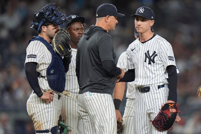 New York Yankees catcher Austin Wells, left, and Jazz Chisholm Jr., second from left watch as pitcher Luke Weaver, right, hands the ball to manager Aaron Boone as he leaves during the eighth inning of a baseball game against the Baltimore Orioles Friday, June 20, 2025, in New York. (AP Photo/Frank Franklin II)