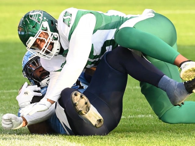 Toronto Argonauts running back Miyan Williams (bottom) is tackled by Saskatchewan Roughriders defensive lineman Habakkuk Baldonado (95) during first half CFL football action in Toronto Friday, June 20, 2025.