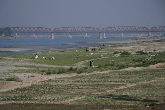 People walk next to a cultivated land on the dry riverbed of the Indus River in Hyderabad, Pakistan April 25, 2025. REUTERS/Yasir Rajput/File Photo