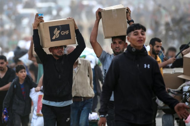 People carry supplies from a Gaza Humanitarian Foundation distribution centre in the central Gaza Strip