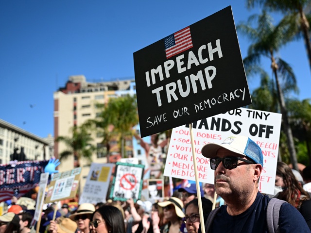 A protester holds a sign reading "Impeach Trump" in Pershing Square before marching to Los Angeles City Hall during a "Hands Off!" rally in opposition to the Trump administration on April 05, 2025 in Los Angeles, California. Protests against Trump administration policies and Elon Musk's Department of Government Efficiency (DOGE) are being held nationwide in what organizers are calling a National Day of Action. (Photo by Sarah Morris/Getty Images)