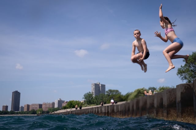 Lewis Moore, 9, left, jumps off the pier at Montrose Beach, alongside his sister, Cora Moore, 7, on June 21, 2025, in Chicago, which is under an extreme heat warning this weekend. (Audrey Richardson/Chicago Tribune)