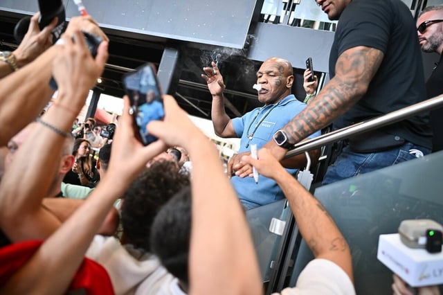 Der Boxer Mike Tyson raucht einen Joint, um ihn herum stehen Menschen die das mit ihren Handys filmen