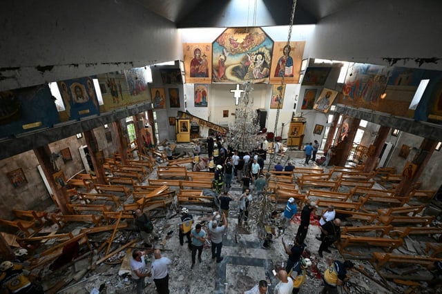 People inspect the damage at the site of a suspected suicide attack at the Saint Elias church in Damascus