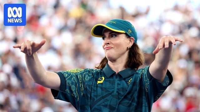 Mid shot of Rachael Gunn wearing Olympic uniform, blurred out crowd behind, pulling face and throwing hands forward.