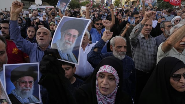 Protesters chant slogans as they hold up posters of the Iranian Supreme Leader Ayatollah Ali Khamenei in a protest following the US attacks.