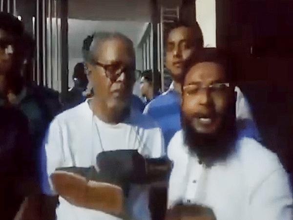 Screengrab from a viral video showing former Bangladesh CEC Nurul Huda with shoes around his neck, surrounded by a group of people | ANI