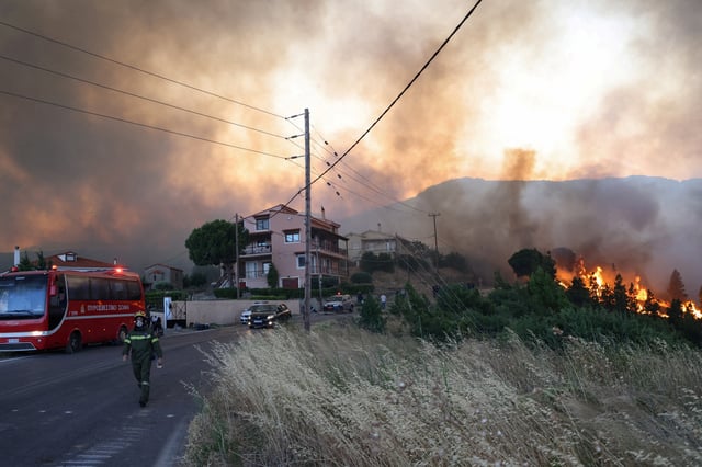 A fireman walks as wildfire, fanned by strong winds, approaches residential areas near the village of Karyes on Chios island, Greece, June 22, 2025. REUTERS/Kostas Anagnostou