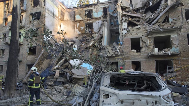 Firefighters work in a destroyed apartment building after a Russian attack in Kyiv, Ukraine, 