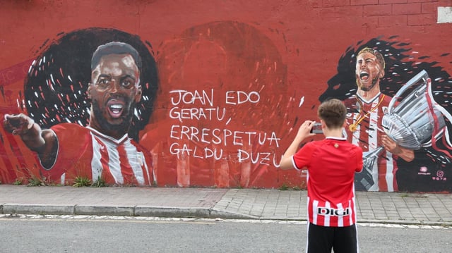 Un aficionado del Athletic realiza una foto del mural en Barakaldo donde se suprimió la imagen de Nico Williams entre Iñaki y Muniain.
