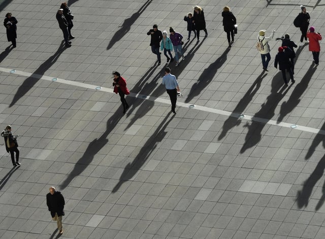 People cast long shadows in the winter sunlight as they walk across a plaza in the Canary Wharf financial district of London, Britain, January 17, 2018. REUTERS/Dylan Martinez/File Photo