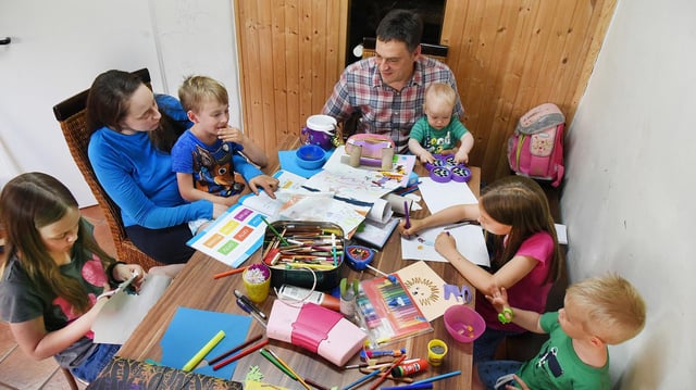 Eltern mit ihren fünf Kindern sitzen an einem Tisch.