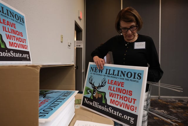 Paula Jablonski, of Cook County, grabs lawn signs about New Illinois from a box during the New Illinois Seventh Constitutional Convention on April 5, 2025, in Bloomington. (John J. Kim/Chicago Tribune)