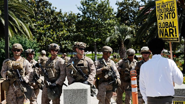 A demonstrator protests near US Marines guarding the Wilshire Federal Building during a rally opposing the US strikes in Iran. (Source: AFP)