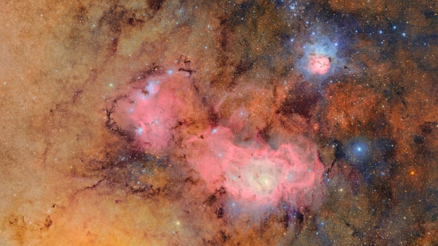 Cette image combine 678 images distinctes prises par l’observatoire Vera Rubin en un peu plus de sept heures d’observation. Leur combinaison révèle des détails extrêmement ténus, tels que les nuages de gaz et de poussière qui composent la nébuleuse Trifide (en haut à droite) et la nébuleuse de la Lagune, situées à plusieurs milliers d’années-lumière de la Terre.