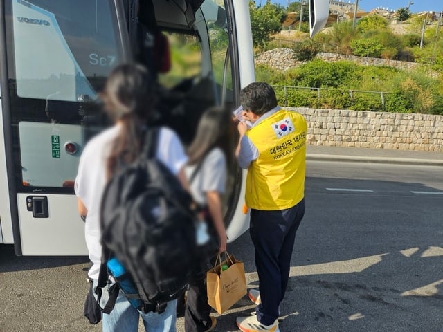 An official from the South Korean Embassy in Israel helps Korean nationals board a bus to a border area as part of an evacuation to Egypt amid the escalating conflict between Israel and Iran, in this photo provided by Seoul's foreign ministry on June 23, 2025. (PHOTO NOT FOR SALE) (Yonhap) 