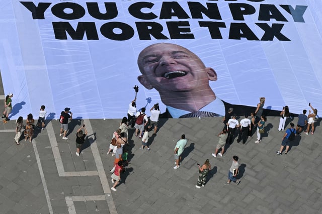 Activists of the international environmental group Greenpeace deploy a giant banner displaying a picture of Jeff Bezos and reading &#34;If you can rent Venice for your wedding you can pay more tax&#34; at St Mark square in Venice on June 23, 2025.