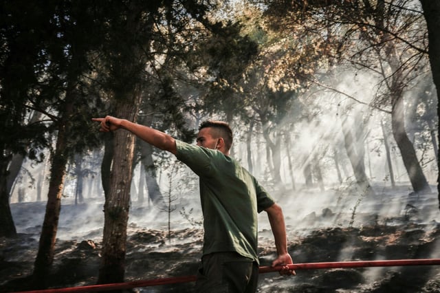 Un volontaire fait un geste en luttant contre un incendie de forêt le 23 juin 2025 sur l'île de Chios en Grèce