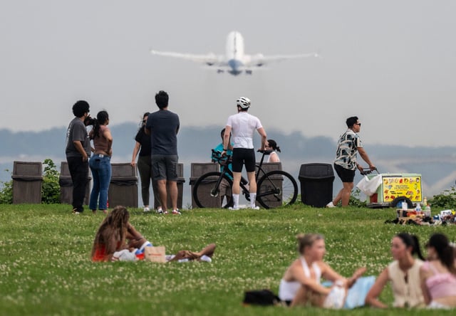 A vendor sells ice cream as people watch a plane take off at Gravely Point during a severe heat wave in Arlington, Virginia on June 22.