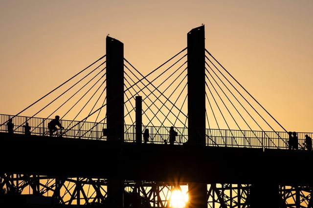 Poeple walk across the Big Four Bridge as the sun sets at Waterfront Park on June 22 in Louisville, Kentucky.