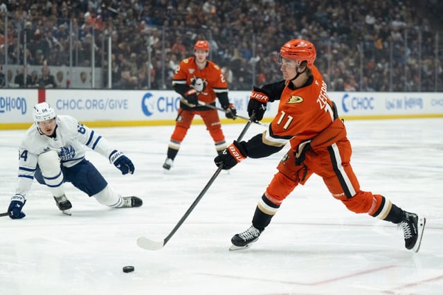 Ducks center Trevor Zegras (11) shoots past Toronto Maple Leafs center David Kampf (64) during the third period of an NHL hockey game, Sunday, March 30, 2025, in Anaheim, Calif. (AP Photo/Kyusung Gong)