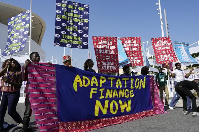Activists participate in a demonstration with a sign that reads "adaptation finance now" at the COP28 U.N. Climate Summit, Friday, Dec. 8, 2023, in Dubai, United Arab Emirates. (AP Photo/Peter Dejong)