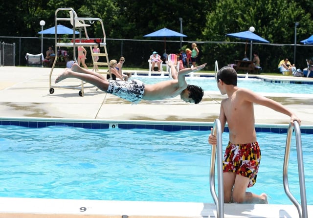 Adam Dono, right, watches as friend Colin Manakil dives in to the pool as they and friends have some fun beating the heat Monday afternoon at the North Harford Swim Club in Jarrettsville.