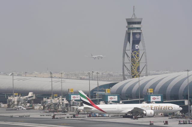 FILE - An Emirates Boeing 777 stands at the gate at Dubai International Airport as another prepares to land on the runway in Dubai, United Arab Emirates, Aug. 17, 2022. (AP Photo/Jon Gambrell, File)