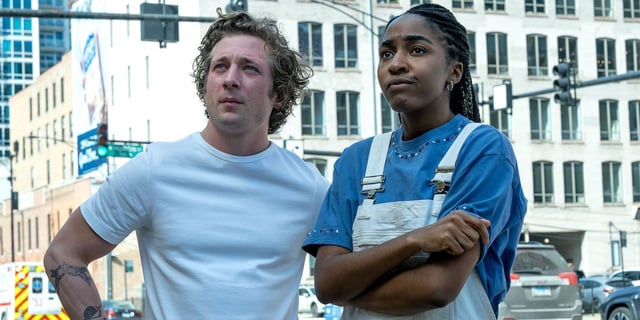 Jeremy Allen White as Carmy and Ayo Edebiri as Sydney standing in the streets looking offscreen contemplatively in The Bear Season 2. 