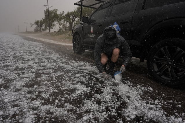 Tony Illenden crouches in a helmet and gloves outside Northern Illinois University's Husky Hail Hunter to scoop hail into a bag during a hailstorm on June 6, 2025, in Levelland, Texas.