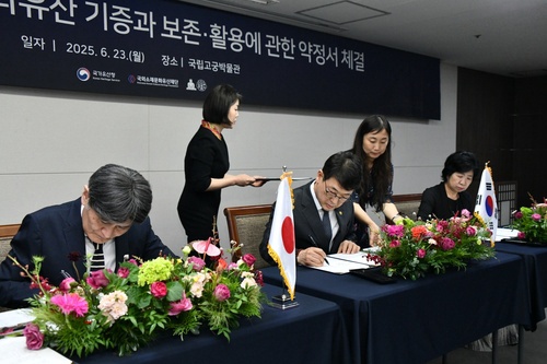 Takao Sato, chief priest of Kotoku-in, a Buddhist temple in Kamakura, Japan; Choi Eung-chon, head of the Korea Heritage Service (KHS); and Kim Jung-hee, head of the Overseas Korean Cultural Heritage Foundation, (from L to R) sign an agreement on the donation of Gwanwoldang, a building believed to be a royal shrine from the Joseon Dynasty (1392-1910), at the National Palace Museum of Korea in Seoul on June 23, 2025, in this photo provided by the KHS. (PHOTO NOT FOR SALE) (Yonhap)