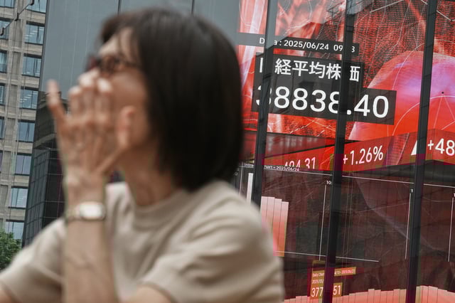 A person stands in front of an electronic stock board showing Japan's Nikkei index at a securities firm Tuesday, June 24, 2025, in Tokyo. (AP Photo/Eugene Hoshiko)