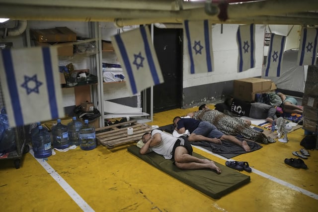 People rest and as they take shelter in an underground parking garage as a precaution against possible Iranian missile attacks, in Tel Aviv, Israel, Tuesday, June 24, 2025. (AP Photo/Ohad Zwigenberg)