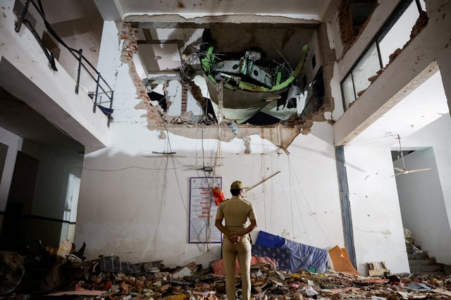 A police officer stands in front of the wreckage of an Air India aircraft, bound for London's Gatwick Airport, which crashed and landed on a hostel building minutes after take-off from an airport in Ahmedabad, India June 12, 2025. REUTERS/Adnan Abidi/File Photo