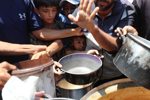 Palestinians wait to receive food cooked by a charity kitchen, in Gaza City, June 21, 2025. REUTERS/Mahmoud Issa/File Photo