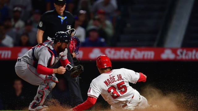 Jun 23, 2025; Anaheim, California, USA; Los Angeles Angels right fielder LaMonte Wade Jr. (35) scores a run ahead of Boston Red Sox catcher Connor Wong (12) during the eighth inning at Angel Stadium. Mandatory Credit: Gary A. Vasquez-Imagn Images
